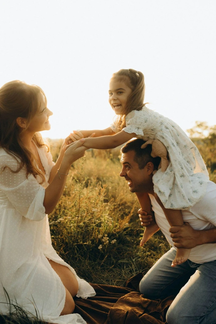 A man holding a little girl on his shoulders